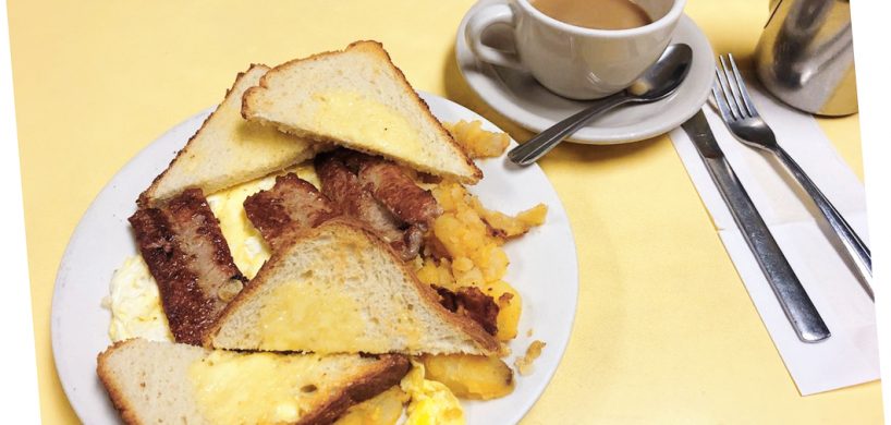 2 Eggs Any Style Platter. This picture D pics a platter with scrambled eggs home fried potatoes and sliced toast on top of a white platter served on Johnny’s yellow counter. It also shows a side order of sausage that is usually an additional charge