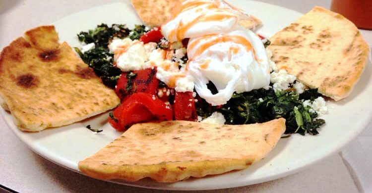 Aidans Way. This picture did pics two poached eggs served on top of a bed of sautéed spinach and roasted peppers, accompanied with a toasted pita cut into four triangular pieces on top of a plate Served on Johny’s original white counter