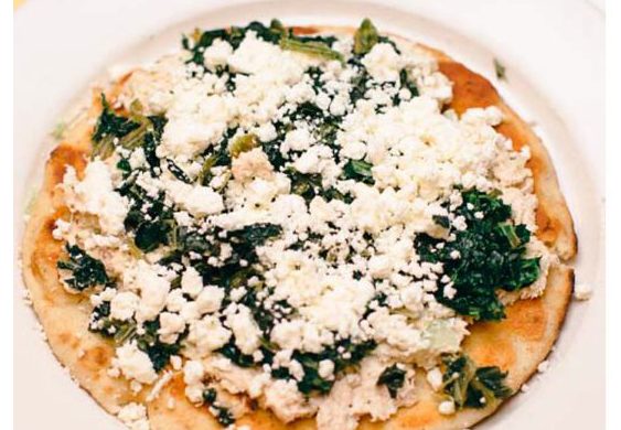 Great Alexander. This picture depicts an order of fresh tuna salad that is topped with spinach and feta cheese served open face on a pita bread that is on a white platter served on Johnys countertop