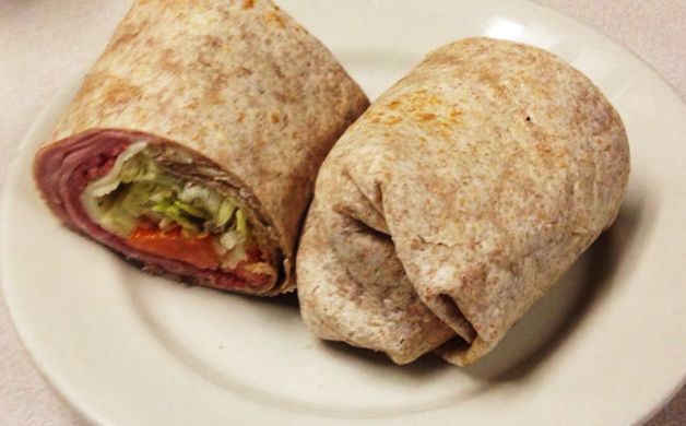 basic wrap sandwich. This picture to pics a basic wrap sandwich that would usually be served on a whole wheat were playing rap that consists of a wide array of meats veggies and cheeses. It is cut in half and served on a white bladder on Johnny’s original Counter top